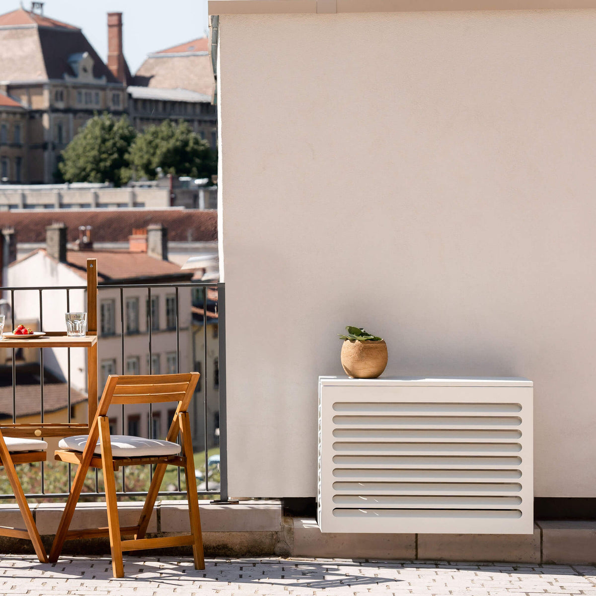 Cache clim gris anthracite (RAL 7016) Cabanaclim – – posé dans un environnement extérieur aménagé. Idéal pour dissimuler une unité extérieure dans un espace déco avec plantes, mobilier outdoor et ambiance architecturale.
